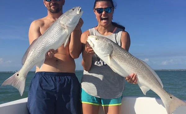 Anglers displaying redfish on a Something Catchy charter
