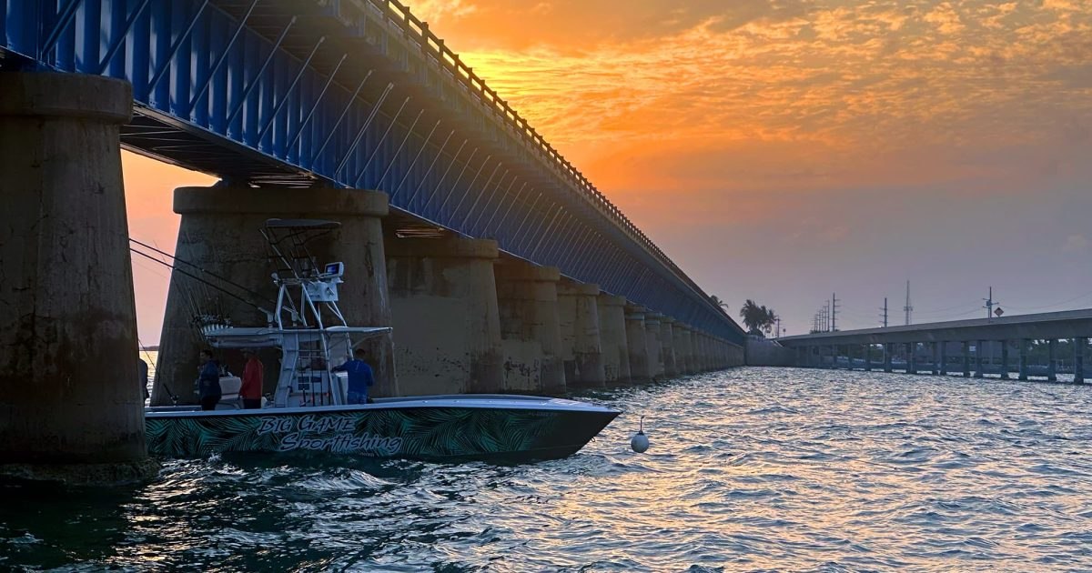 Big Game fishing boat cruising beneath a bridge at sunset