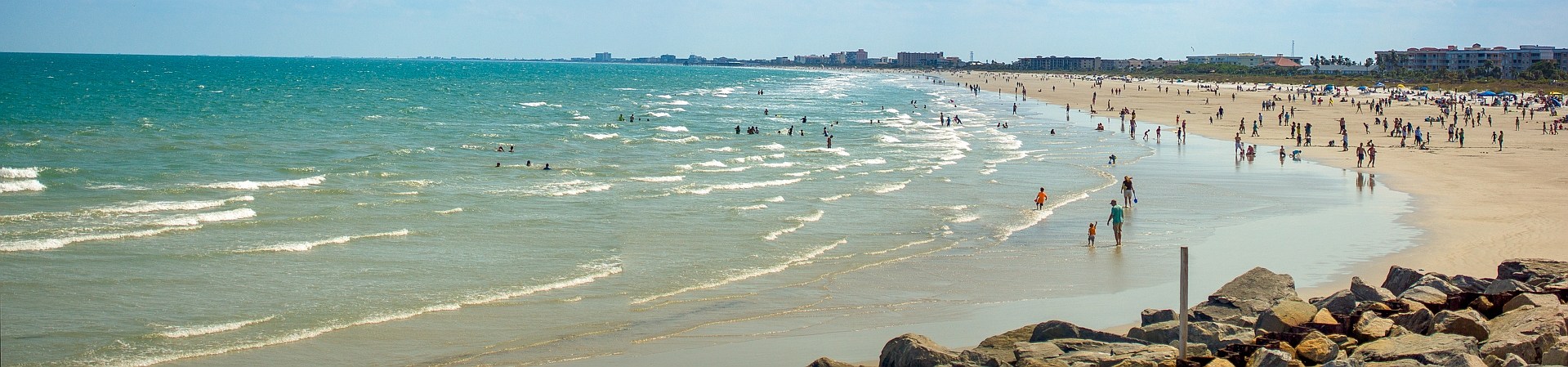 Beachgoers along the Cape Canaveral coast viewed beside jetty rocks