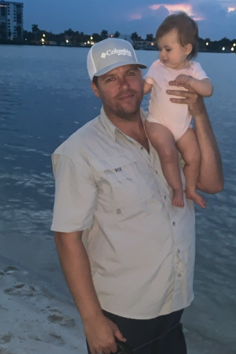 Captain holding a child beside the water in a Trident Charters photograph