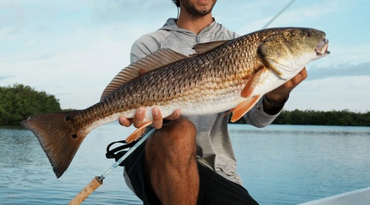 Captain JC holding a redfish aboard his New Port Richey fishing boat