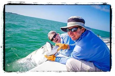 Captain Ozzie Lessinger fishing guests with a tarpon beside the boat