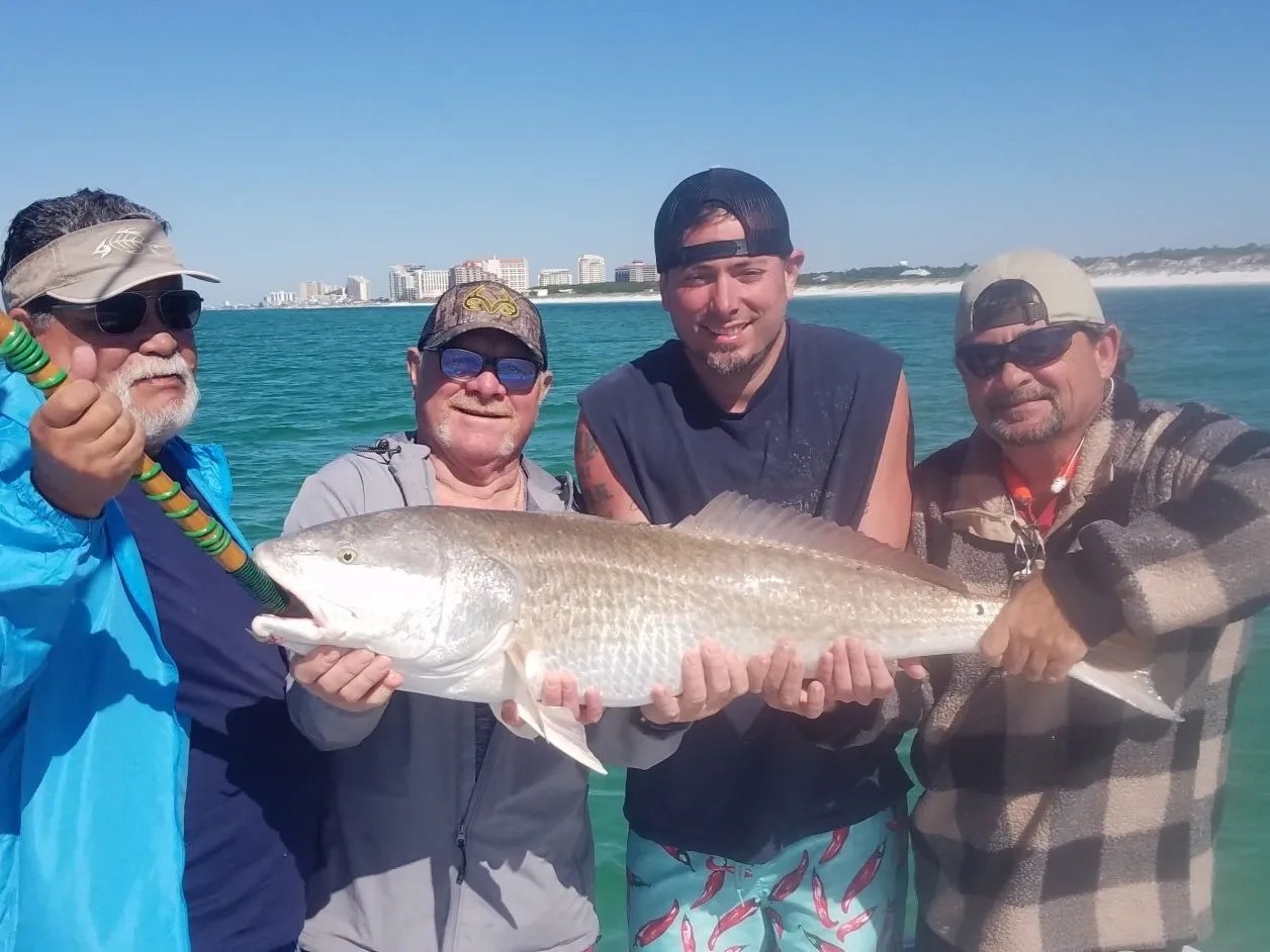 Dawn Patrol fishing group holding a large redfish