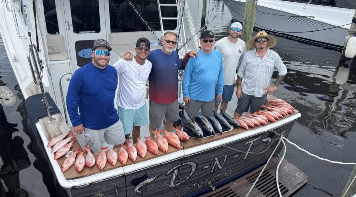 DNT Charters group beside a dockside fish display