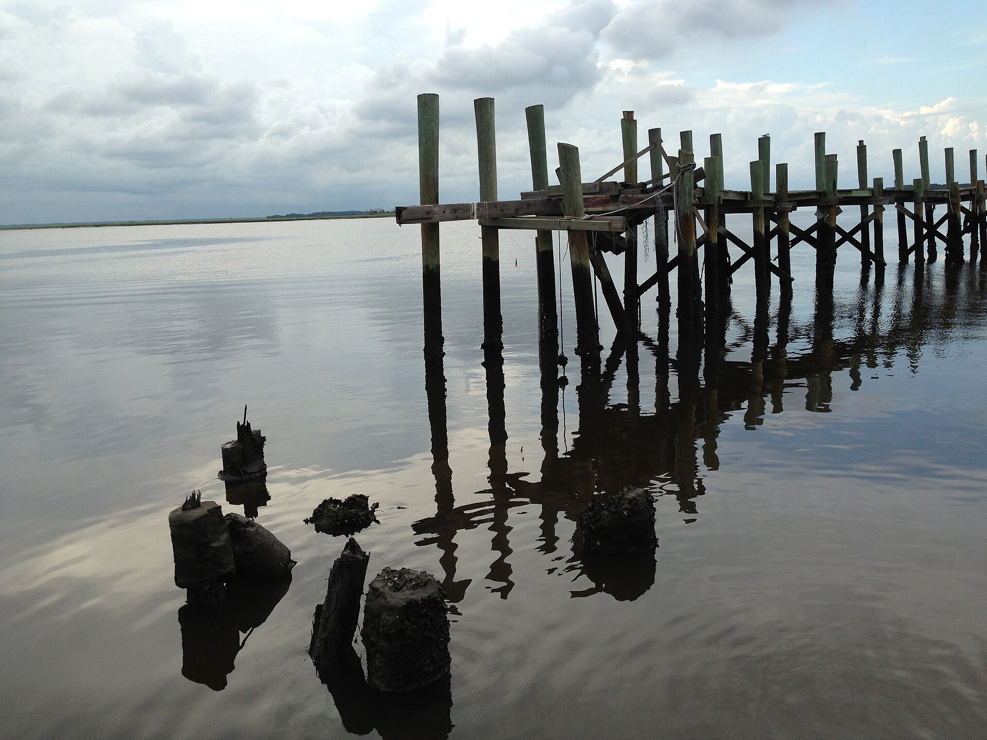 Weathered dock posts reflected in calm water at Fernandina Beach