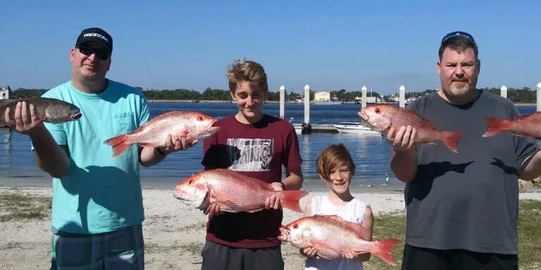 Fishbuster family fishing group displaying red snapper at the dock