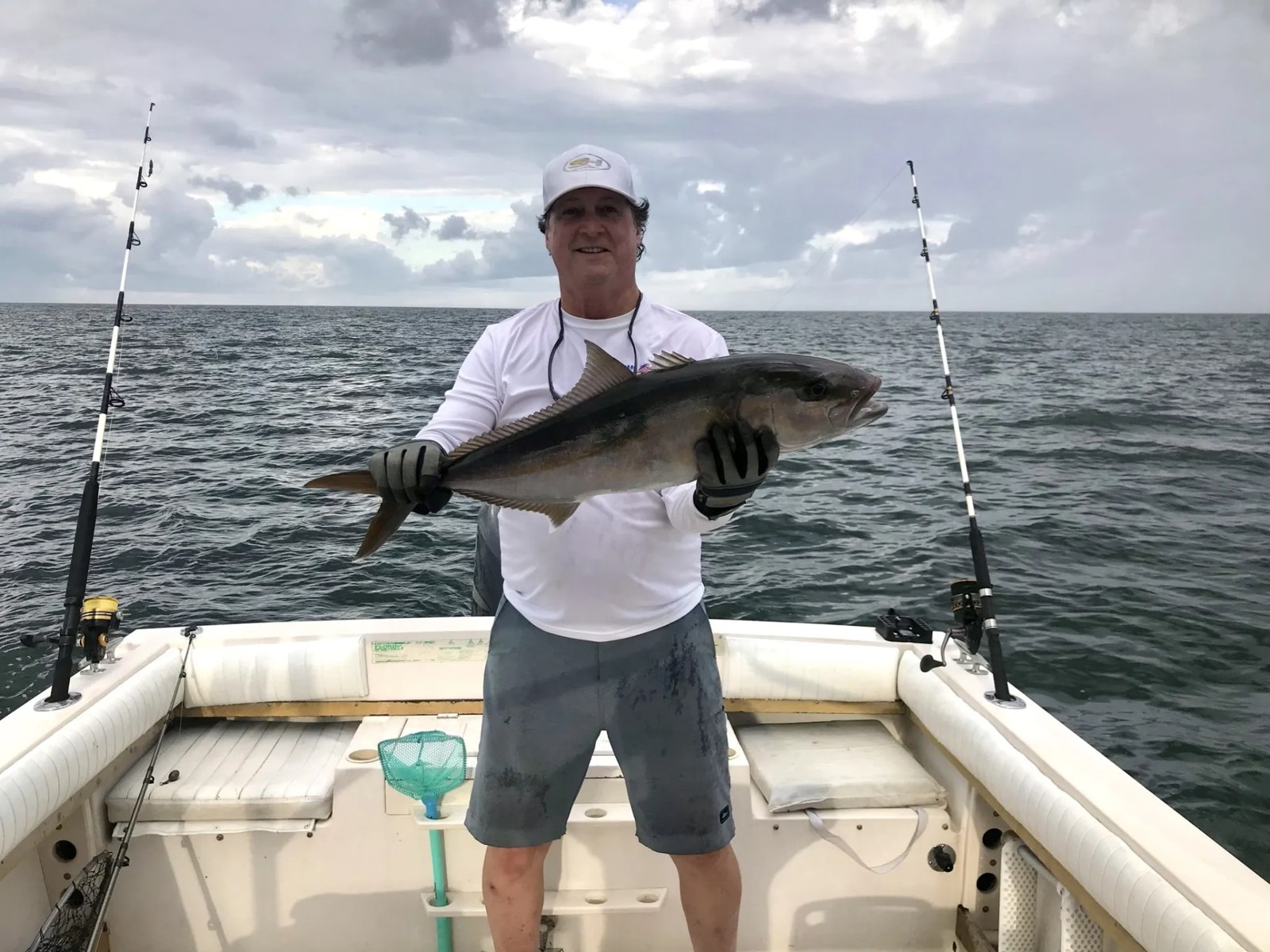 Fishing guest holding a large dark fish aboard the boat