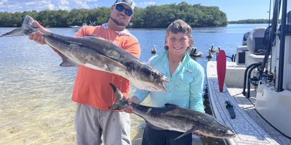 Florida Raised Fishing Adventures anglers displaying cobia beside a river shoreline