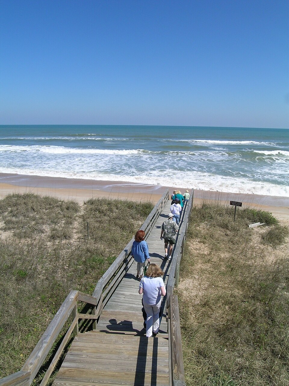Visitors on a boardwalk crossing the dunes at Guana Beach