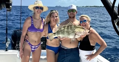 Guests displaying a grouper aboard a No Madda trip