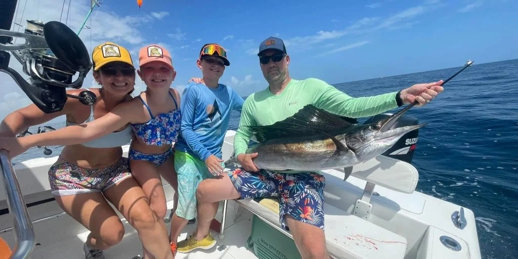 Guests displaying a sailfish alongside the boat