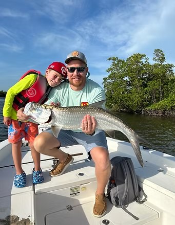 Guide helping a child hold a snook on an Uncharted Adventures outing