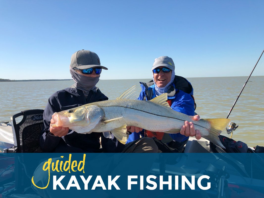 Kayak anglers holding a snook on a Naples Fishing Adventures outing