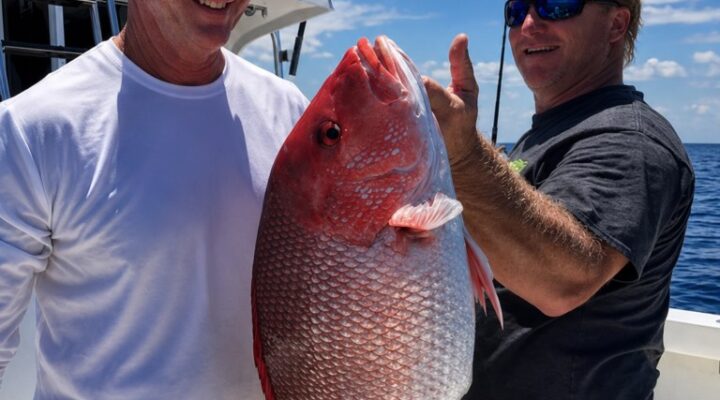 Legend Fishing Charters guests holding a red snapper
