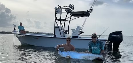 Native Fishing Charters boat beside anglers with a tarpon in the water