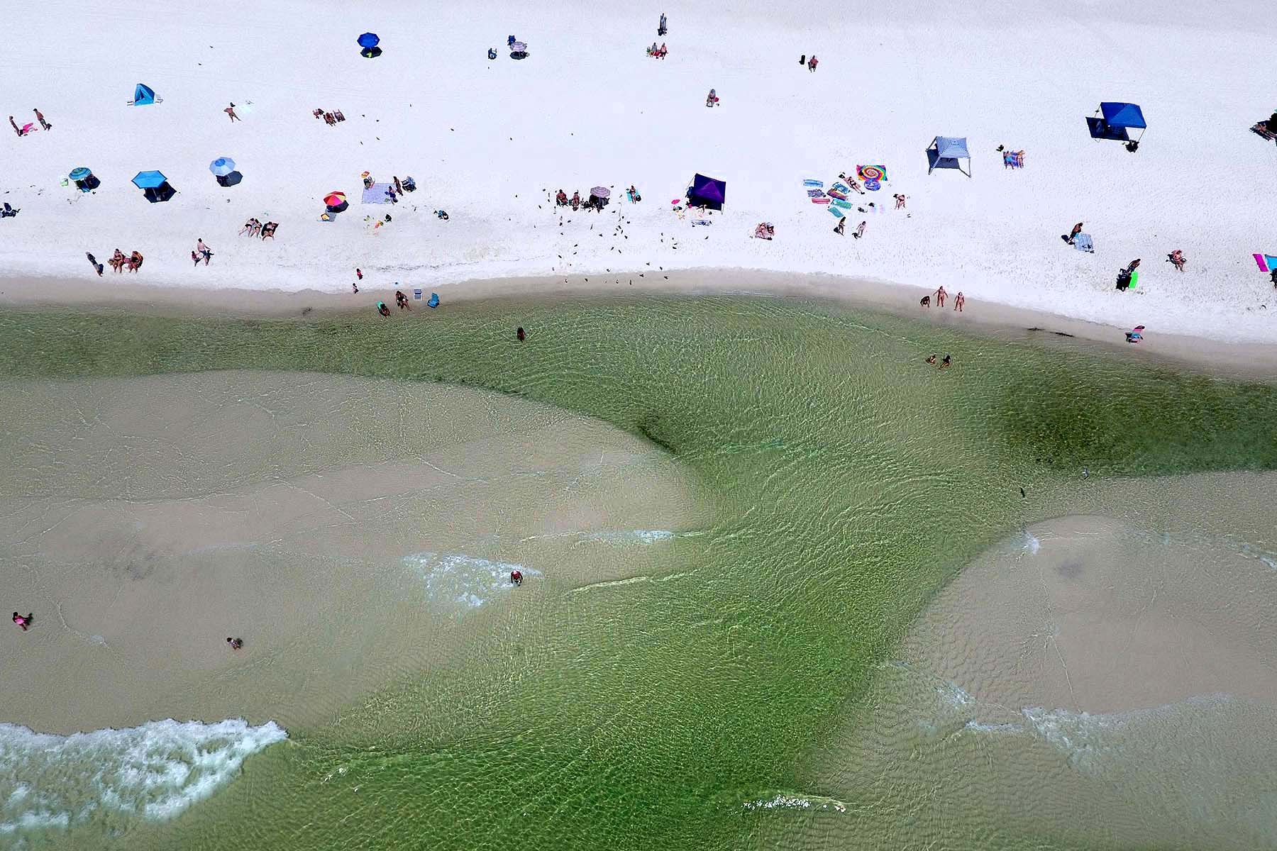 Aerial view of beach visitors and shallow Gulf water beside the Boardwalk on Okaloosa Island