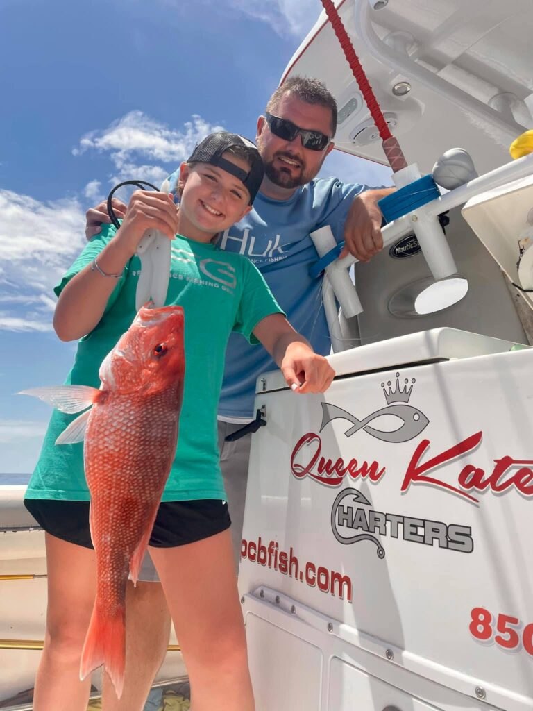 Queen Kate Charters child displaying a mahi beside the boat