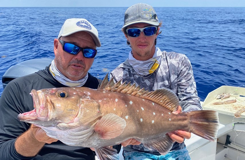 Two anglers displaying a red grouper aboard Florida Boy Charters