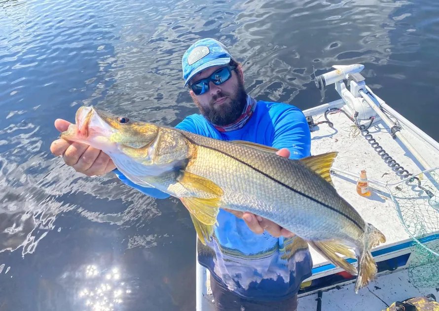 Reel Shallow Fishn angler holding a snook beside the boat