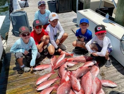 Snapper Trapper family beside a deck of snapper after fishing