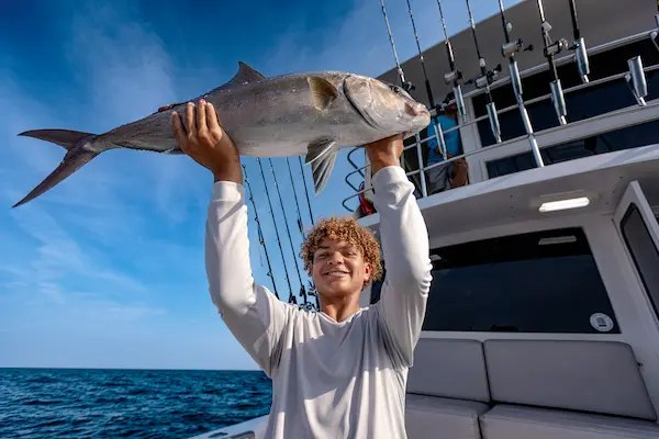 Stelluna angler holding an amberjack on deck