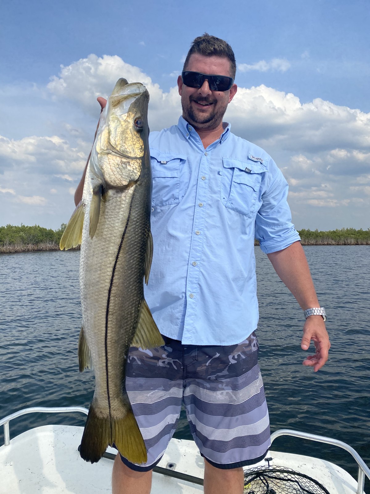 Tried and True angler holding a cobia beside the boat