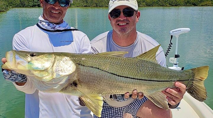 Two anglers displaying a snook on a Triple C Charters trip