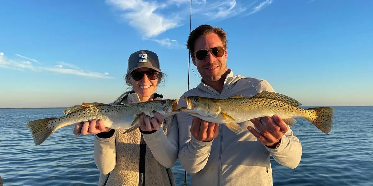 Two anglers displaying redfish with Thrill of It All Charters