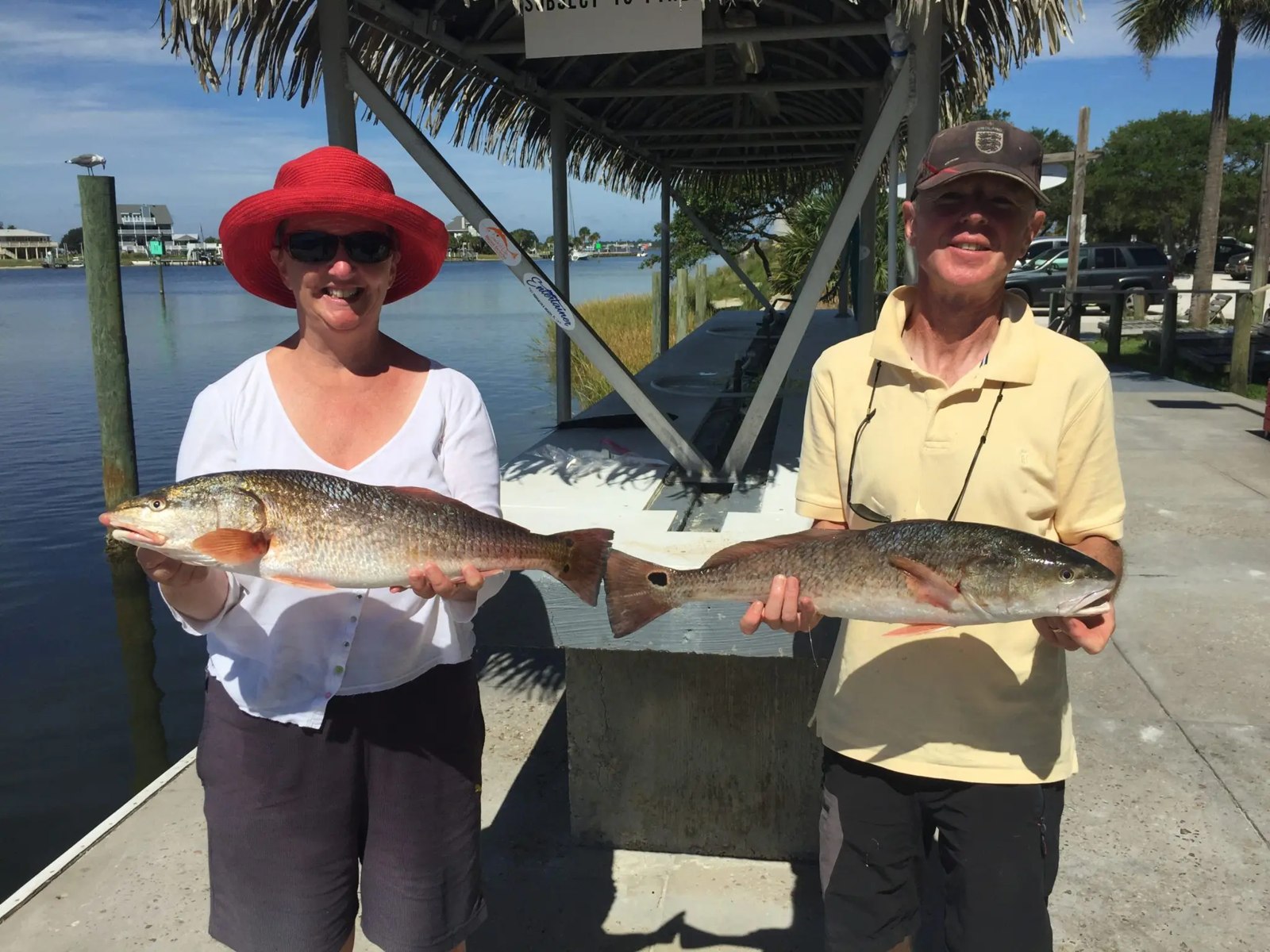 Two Reel Way anglers holding redfish at the dock