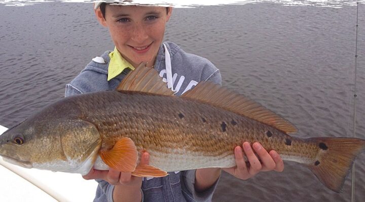 Young angler holding a redfish with Brian Walker Fishing Charters