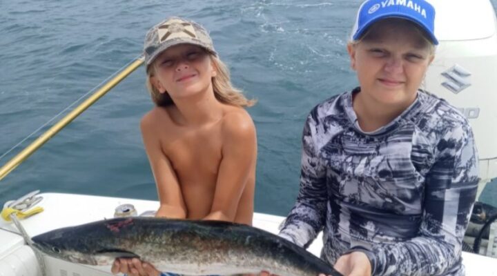 Young anglers displaying a redfish with Conquistador Fishing Charters