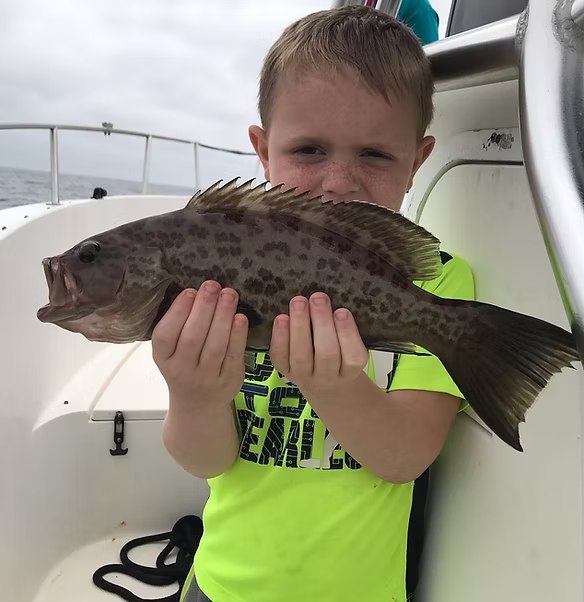 Young Fishing Addiction Charters angler holding a grouper